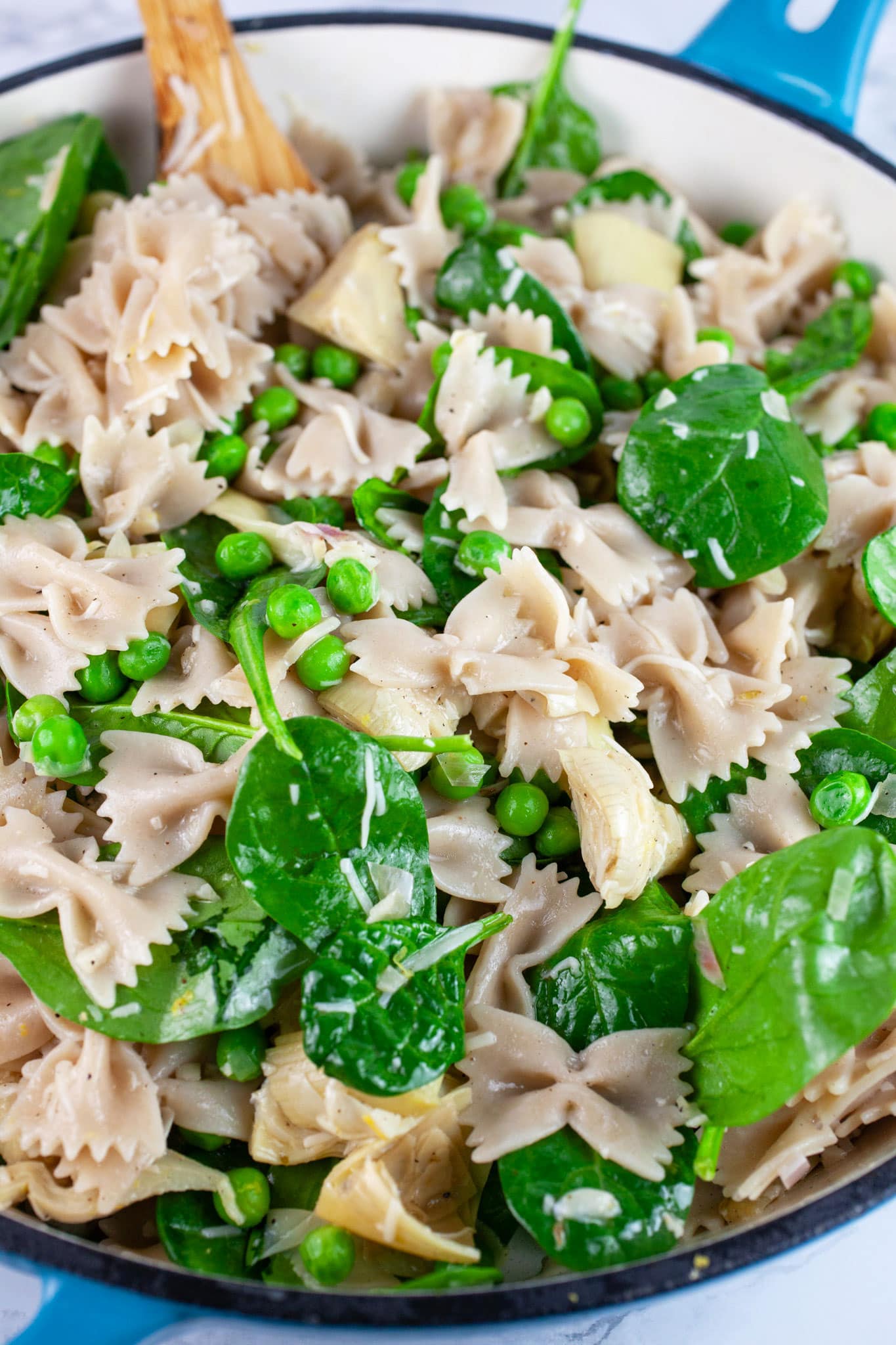 Vegetable pasta in large skillet with wooden spoon.