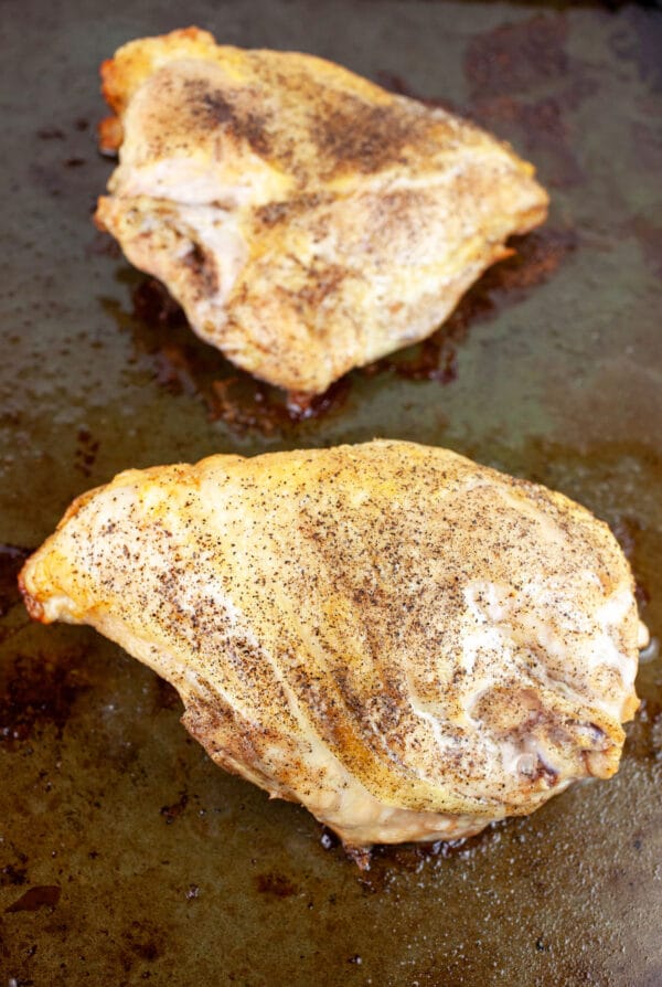 Roasted split chicken breasts on baking sheet.