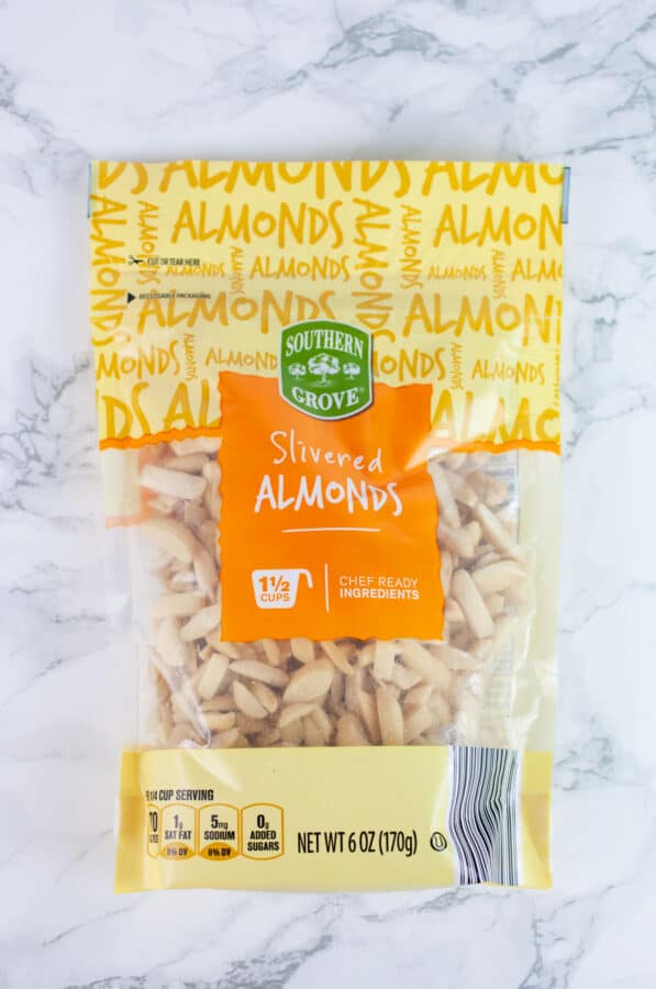 Unopened bag of slivered almonds on white surface.
