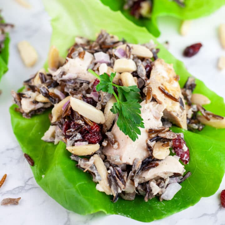 Wild rice chicken salad with cranberries, almonds, and parsley in lettuce cups.