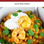 Curry orzo pasta with peas, spinach, shrimp, Greek yogurt, and fresh cilantro in white bowl with fork.