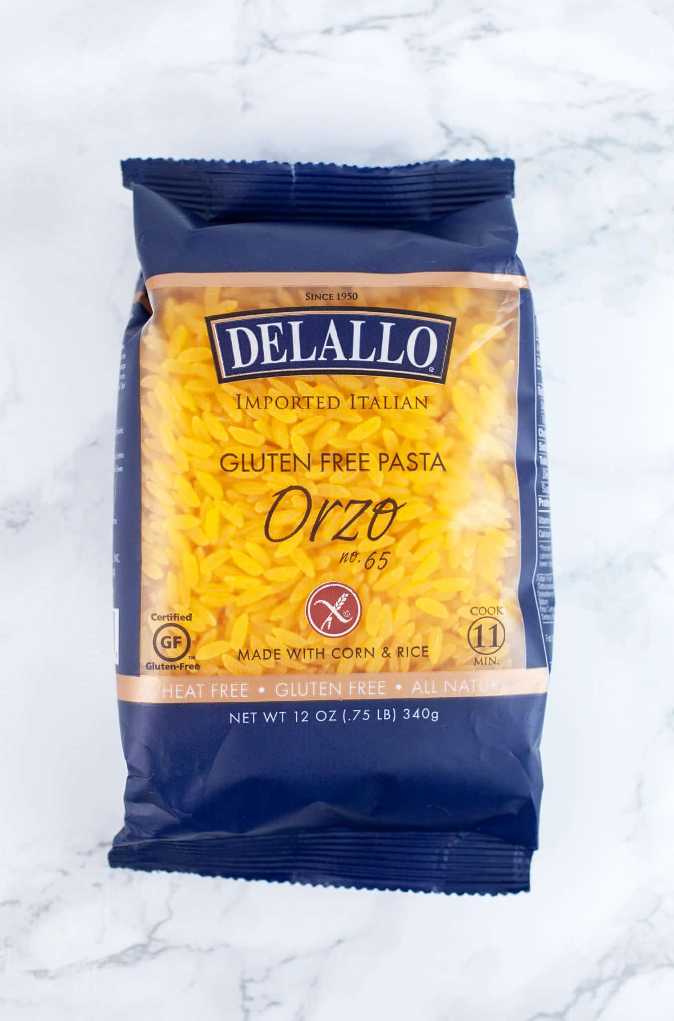 Unopened package of gluten free orzo pasta on white surface.