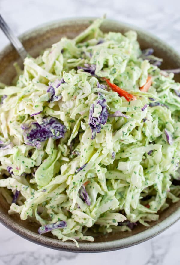 Cilantro lime coleslaw in ceramic bowl with spoon.