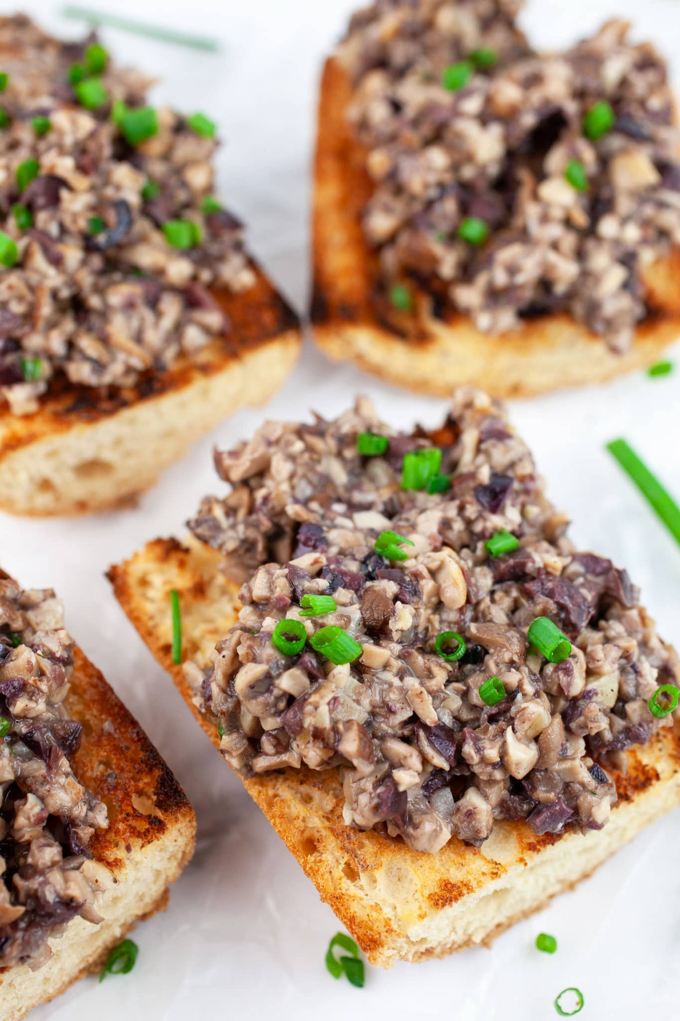 Mushroom tapenade on grilled baguette garnished with fresh chives.