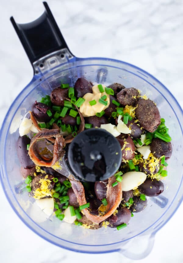 Kalamata olives, Dijon mustard, garlic cloves, lemon juice and zest, anchovy filets, and minced chives in food processor.