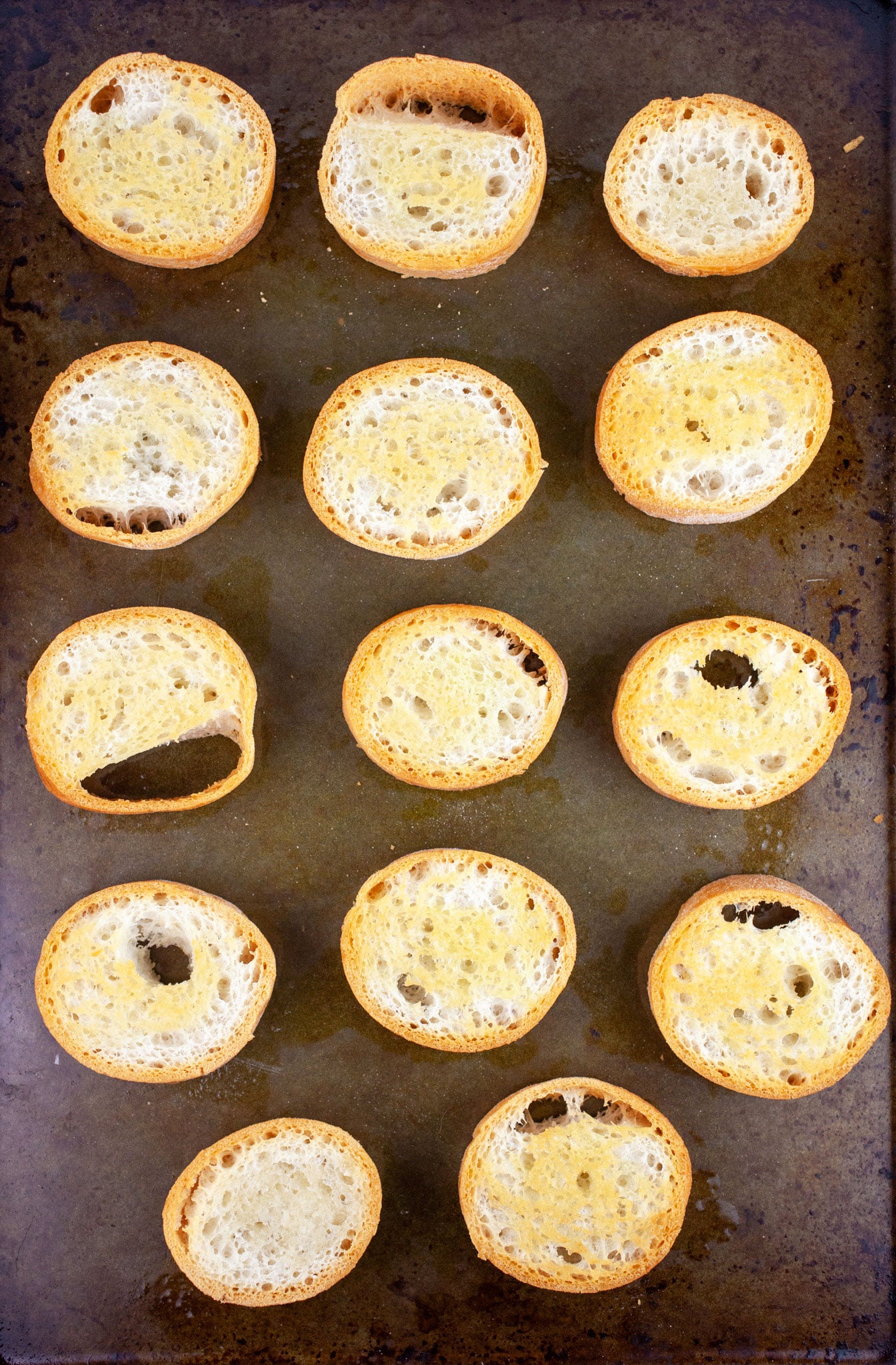 Toasted crostini on baking sheet.