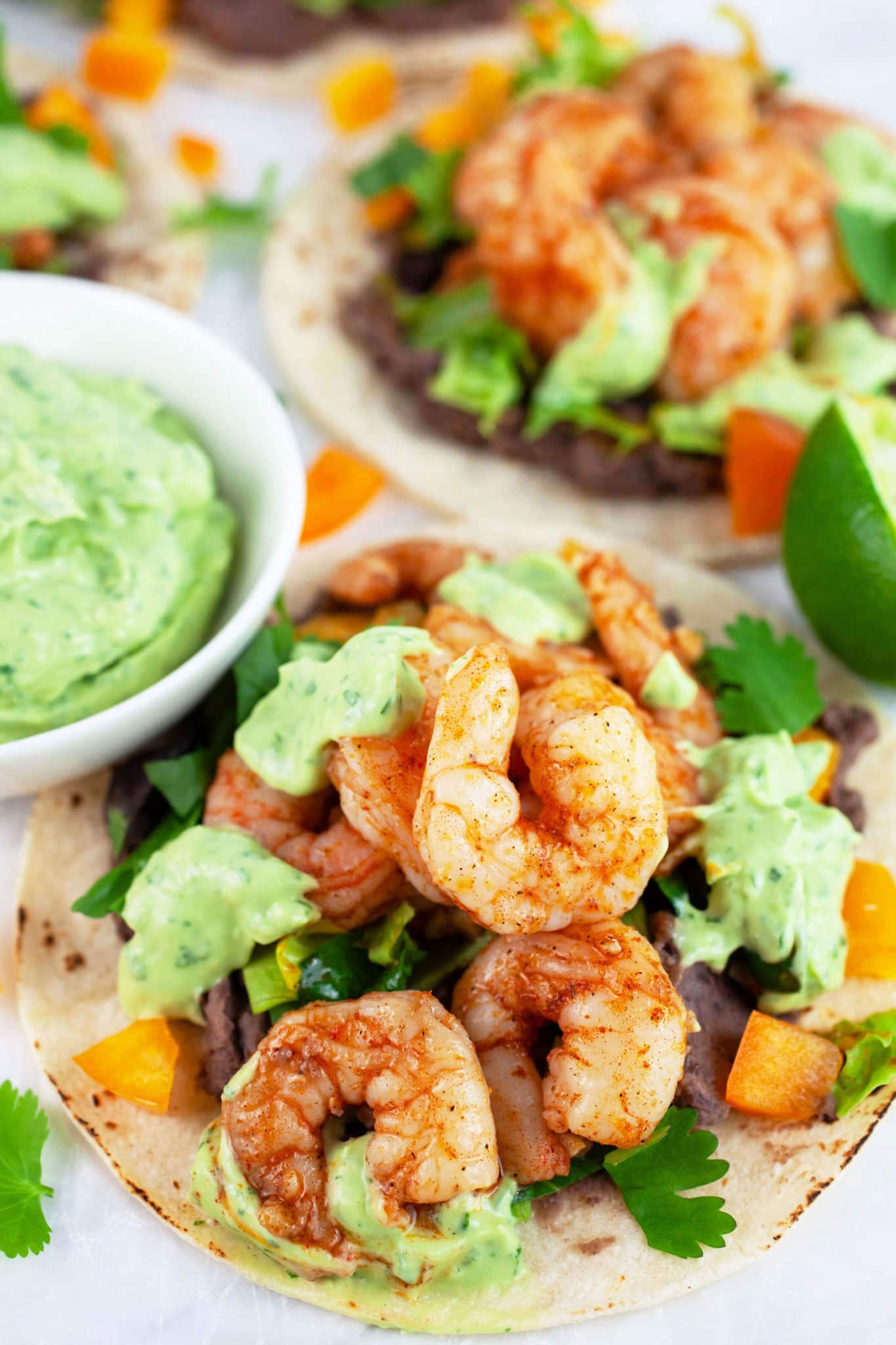 Cajun shrimp tacos with avocado sauce on corn tortillas.