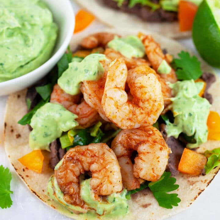 Cajun shrimp tacos with avocado sauce on corn tortillas.