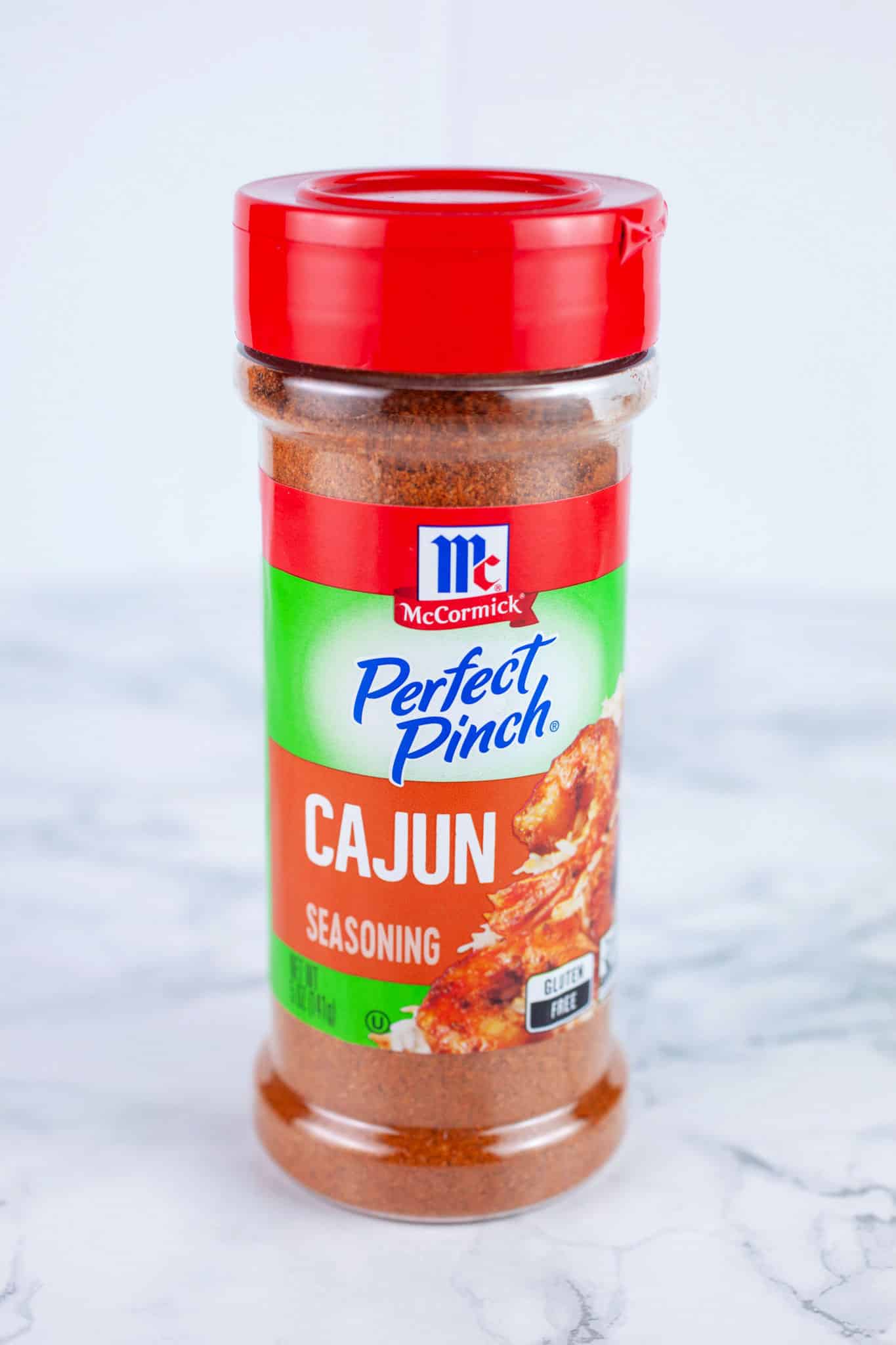 Bottle of Cajun seasoning on white surface.