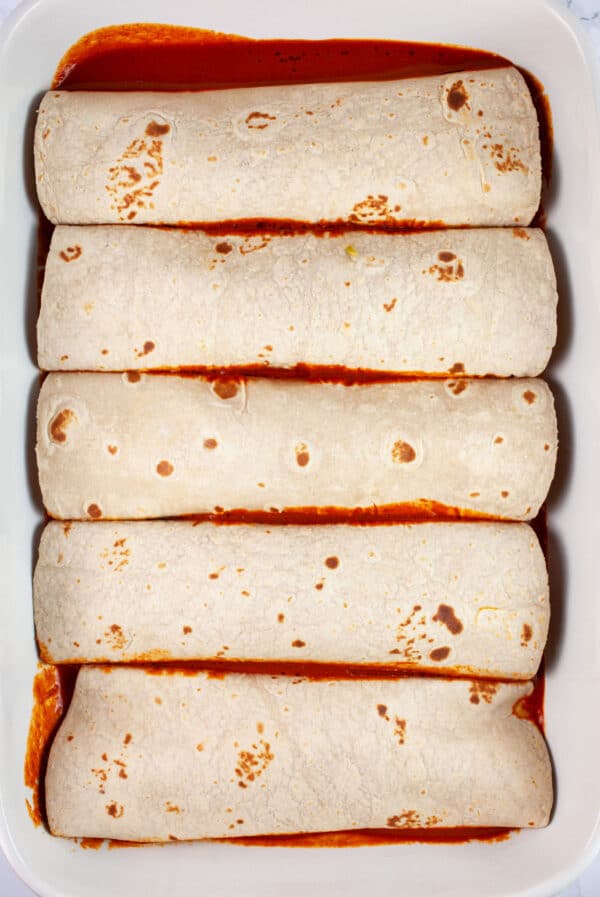 Filled tortillas in ceramic casserole dish.
