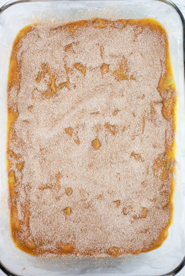 Unbaked rhubarb cake with cinnamon sugar topping in glass baking dish.