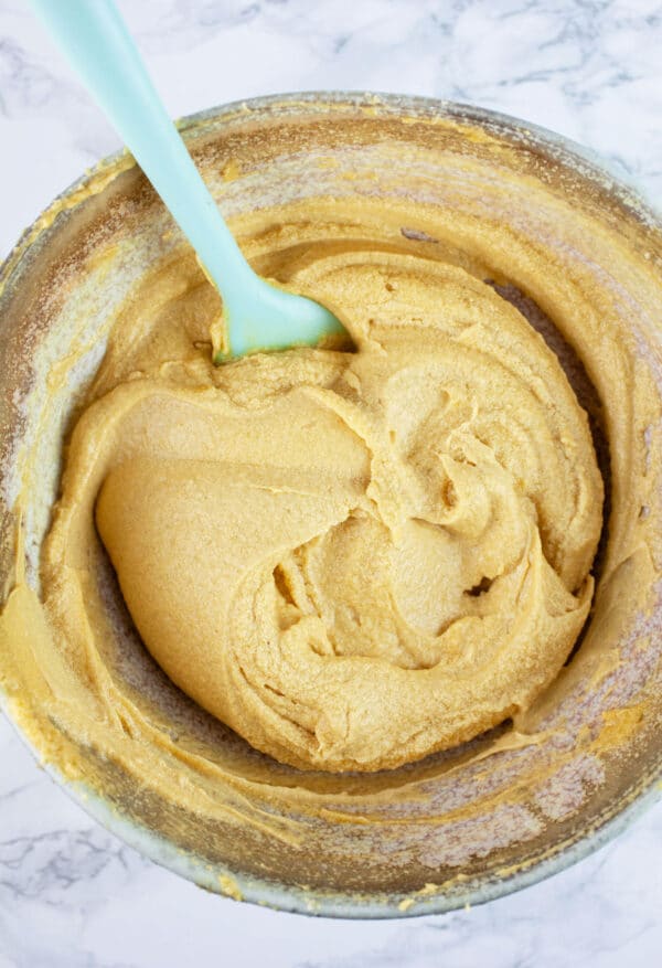 Wet ingredients in ceramic bowl with blue spatula.