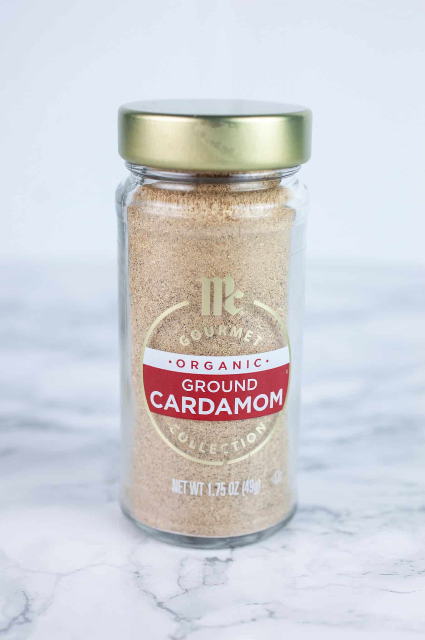 Unopened jar of ground cardamom on white surface.
