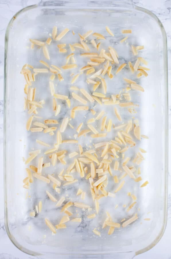 Slivered almonds sprinkled on bottom of glass cake pan.