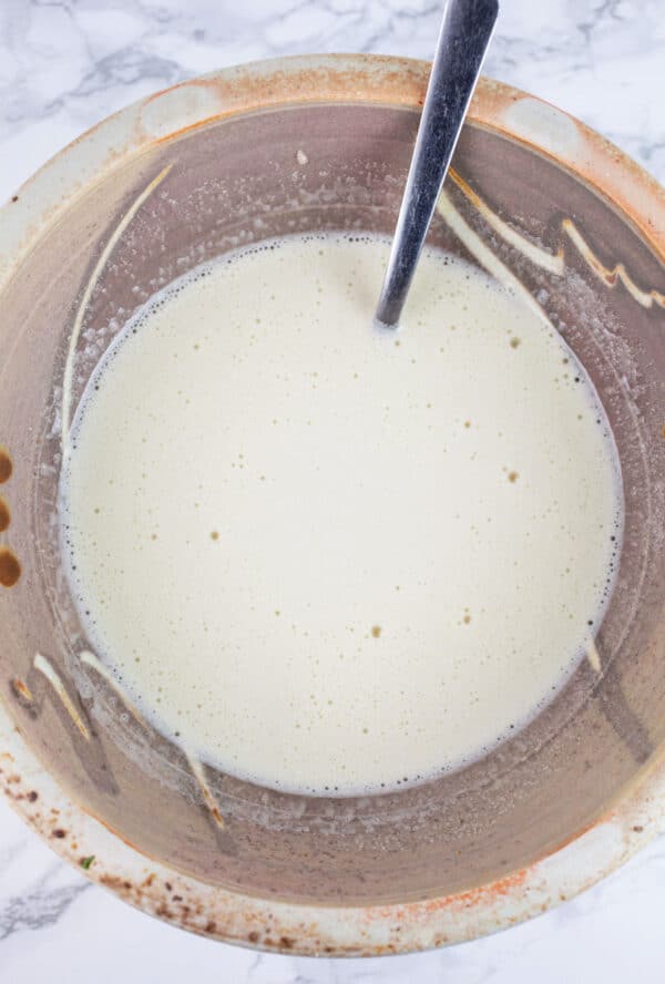 Wet ingredients combined in ceramic bowl with fork.