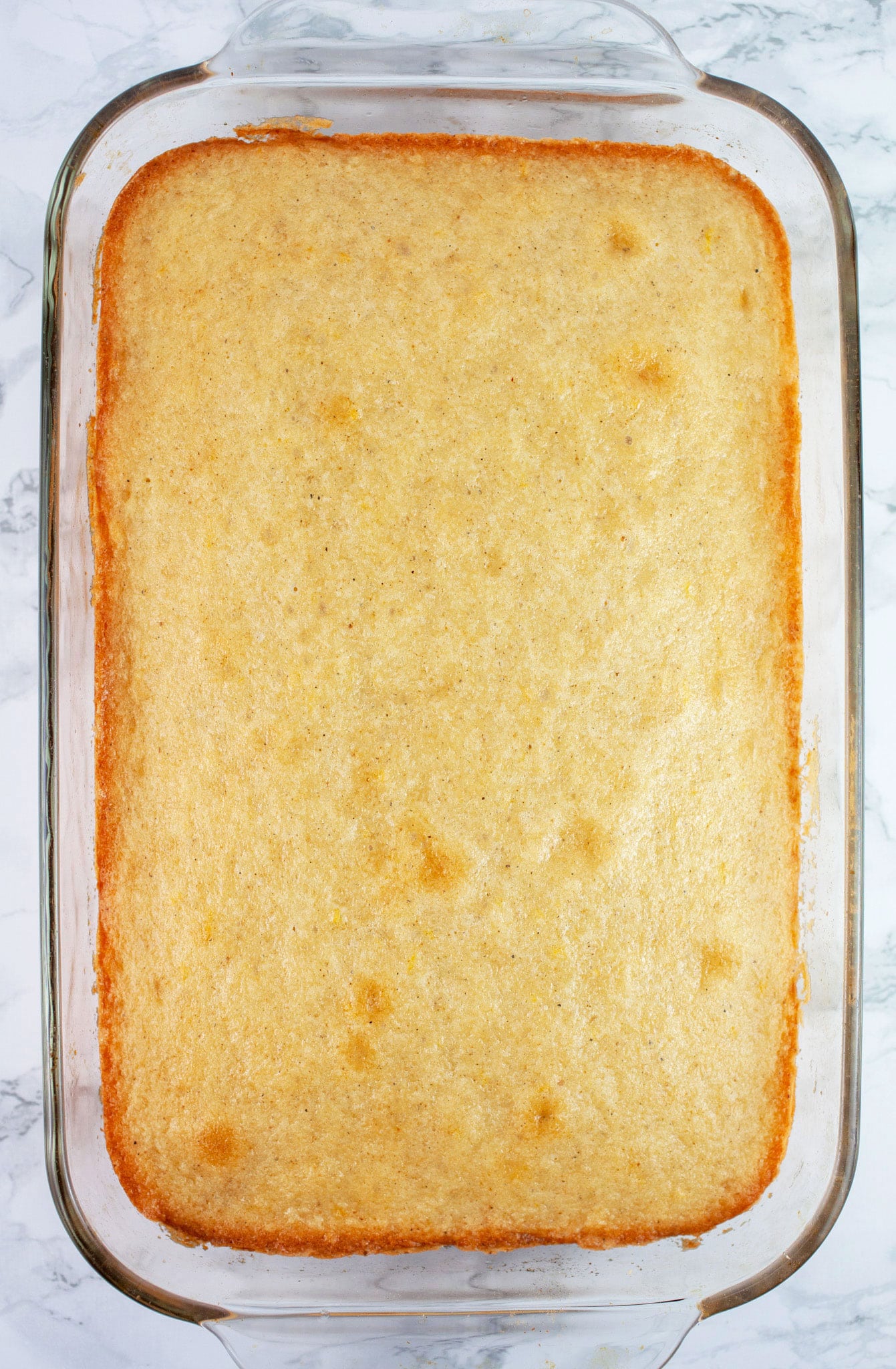 Lemon cardamom cake in glass baking dish.