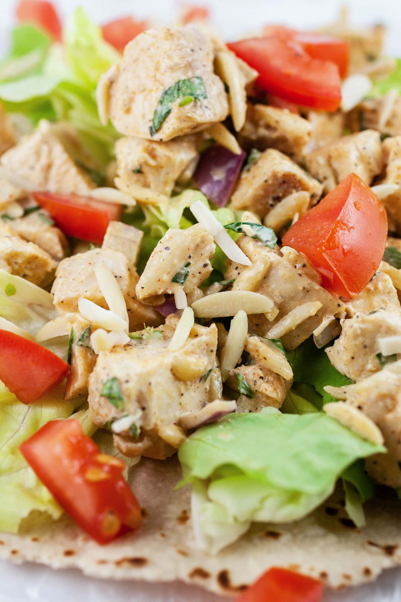 This Lemon Tarragon Chicken Salad recipe is light, healthy, and easy to make! It's flavored with shallots, lemon, and fresh tarragon. Sliced almonds are added for crunch. Add it to a wrap or a sandwich for a simple lunch. This chicken salad is one of the best meals for summer! #tarragon #chicken #chickensalad #lunch #lemon #almonds Lemon tarragon chicken salad with slivered almonds, tomatoes, and lettuce on wrap.