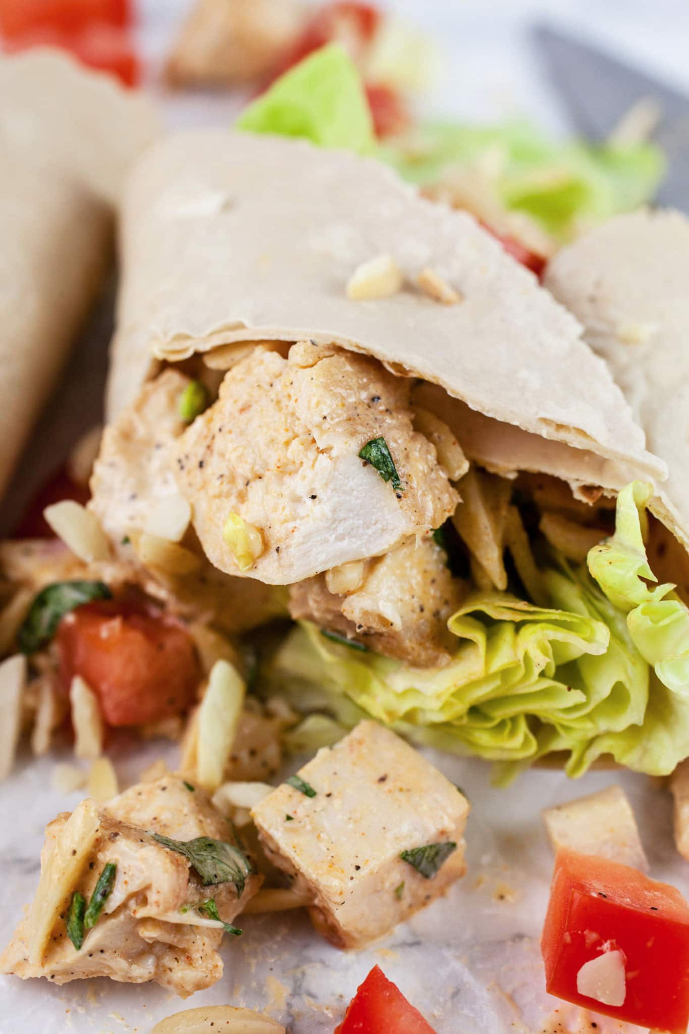 This Lemon Tarragon Chicken Salad recipe is light, healthy, and easy to make! It's flavored with shallots, lemon, and fresh tarragon. Sliced almonds are added for crunch. Add it to a wrap or a sandwich for a simple lunch. This chicken salad is one of the best meals for summer! #tarragon #chicken #chickensalad #lunch #lemon #almonds Tarragon chicken salad in wraps with diced tomatoes and lettuce.