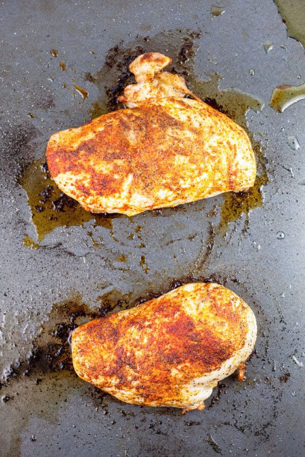 Spiced roasted chicken breasts on baking sheet.