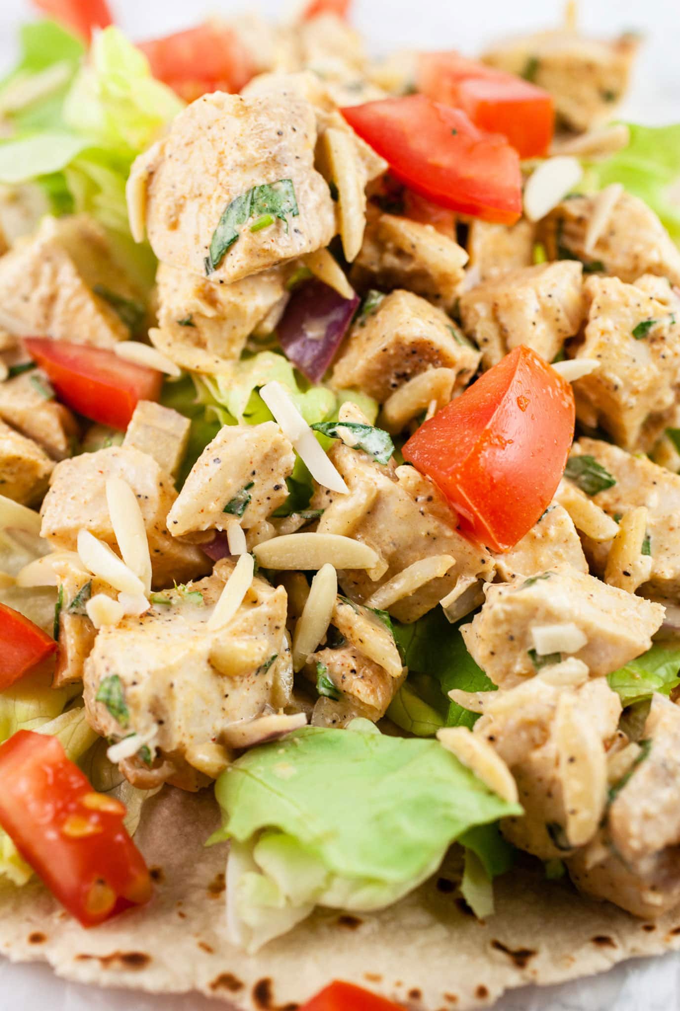 This Lemon Tarragon Chicken Salad recipe is light, healthy, and easy to make! It's flavored with shallots, lemon, and fresh tarragon. Sliced almonds are added for crunch. Add it to a wrap or a sandwich for a simple lunch. This chicken salad is one of the best meals for summer! #tarragon #chicken #chickensalad #lunch #lemon #almonds Lemon tarragon chicken salad with diced tomatoes, lettuce, and slivered almonds on a wrap.