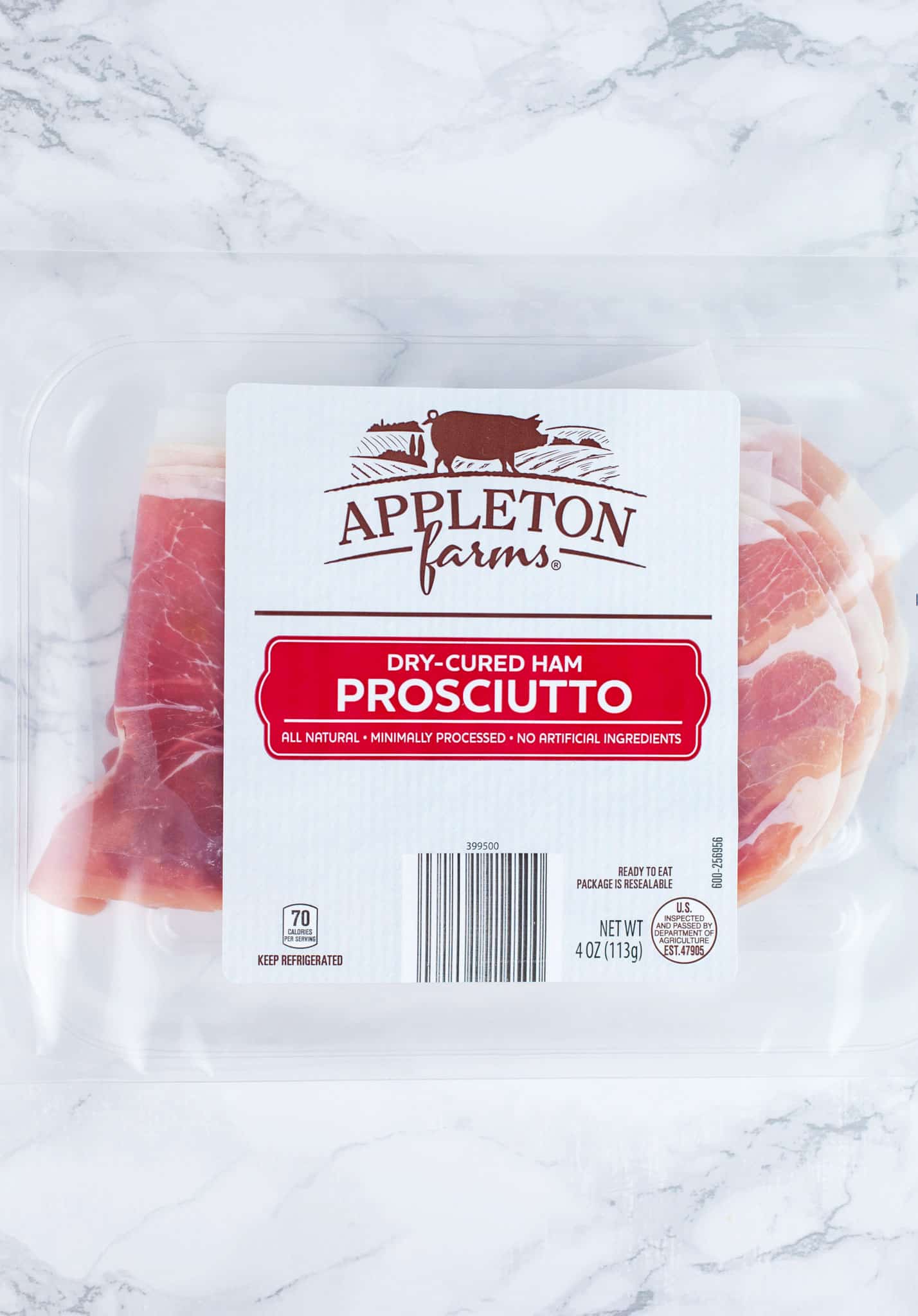 Unopened package of prosciutto on white surface.