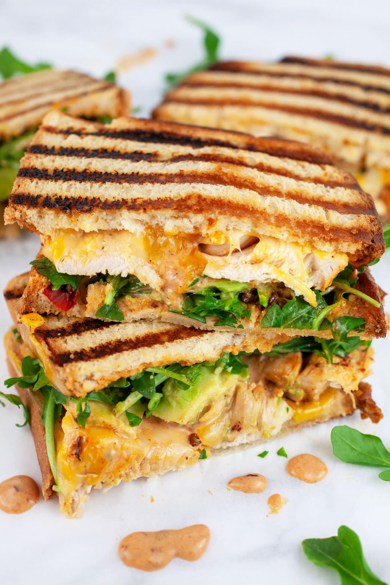 Chipotle chicken panini cut in half and stack on itself on white surface.