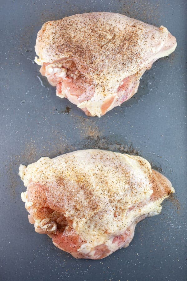 Raw, split chicken breasts on baking sheet.