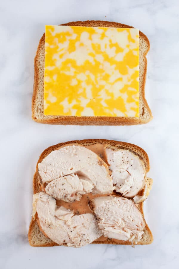 Sliced bread with chipotle mayo, roasted chicken, and slice of cheese.