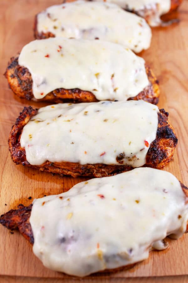 Southwest grilled chicken breasts with Pepper Jack cheese on wooden cutting board.
