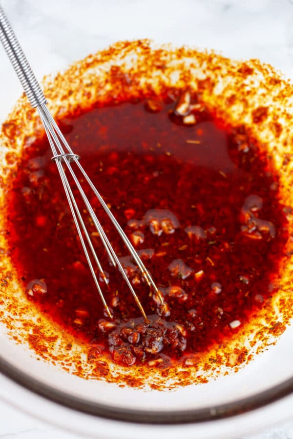Southwest chicken marinade in glass bowl with small whisk.
