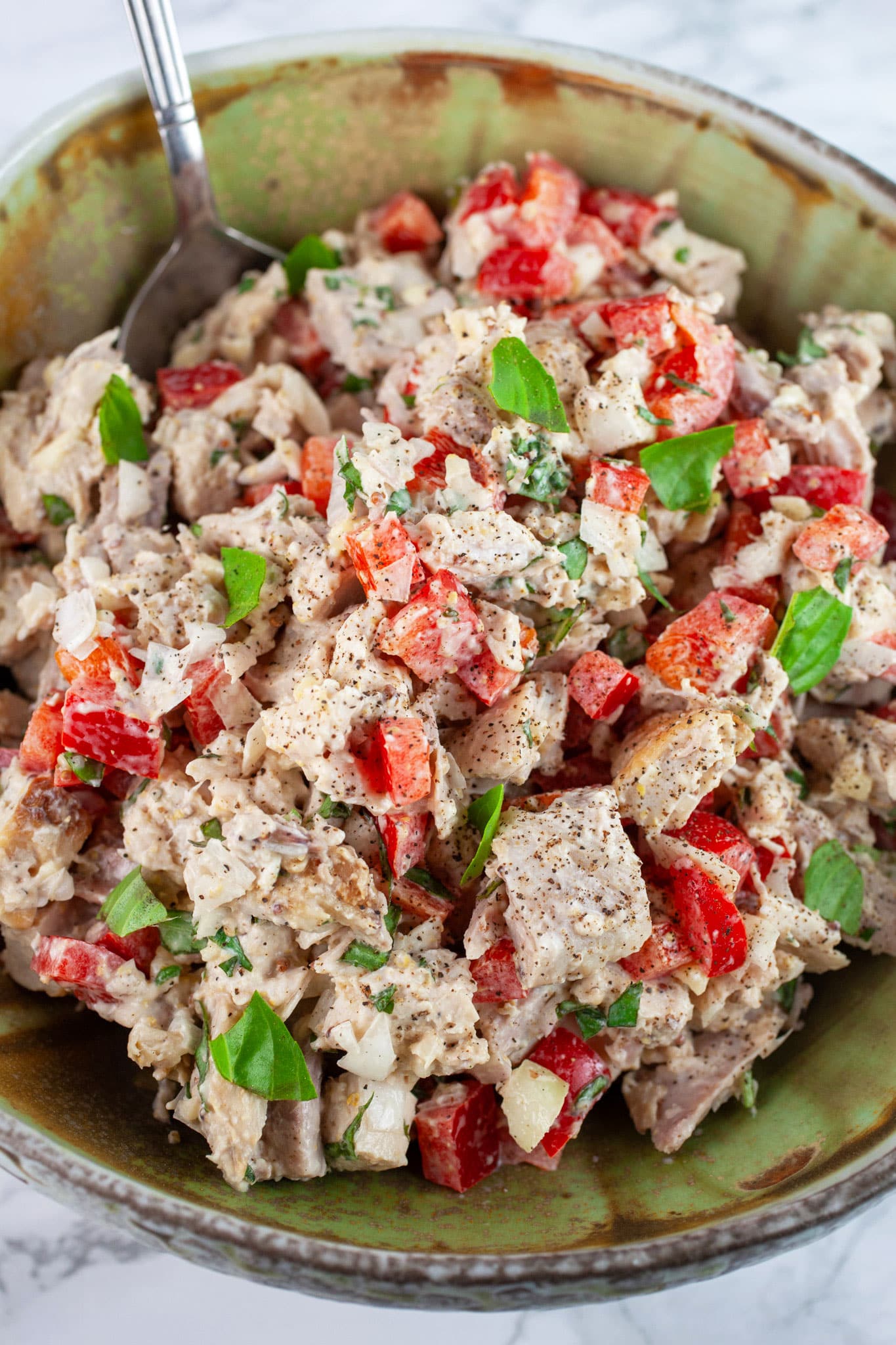 Lemon basil chicken salad in ceramic bowl with spoon.