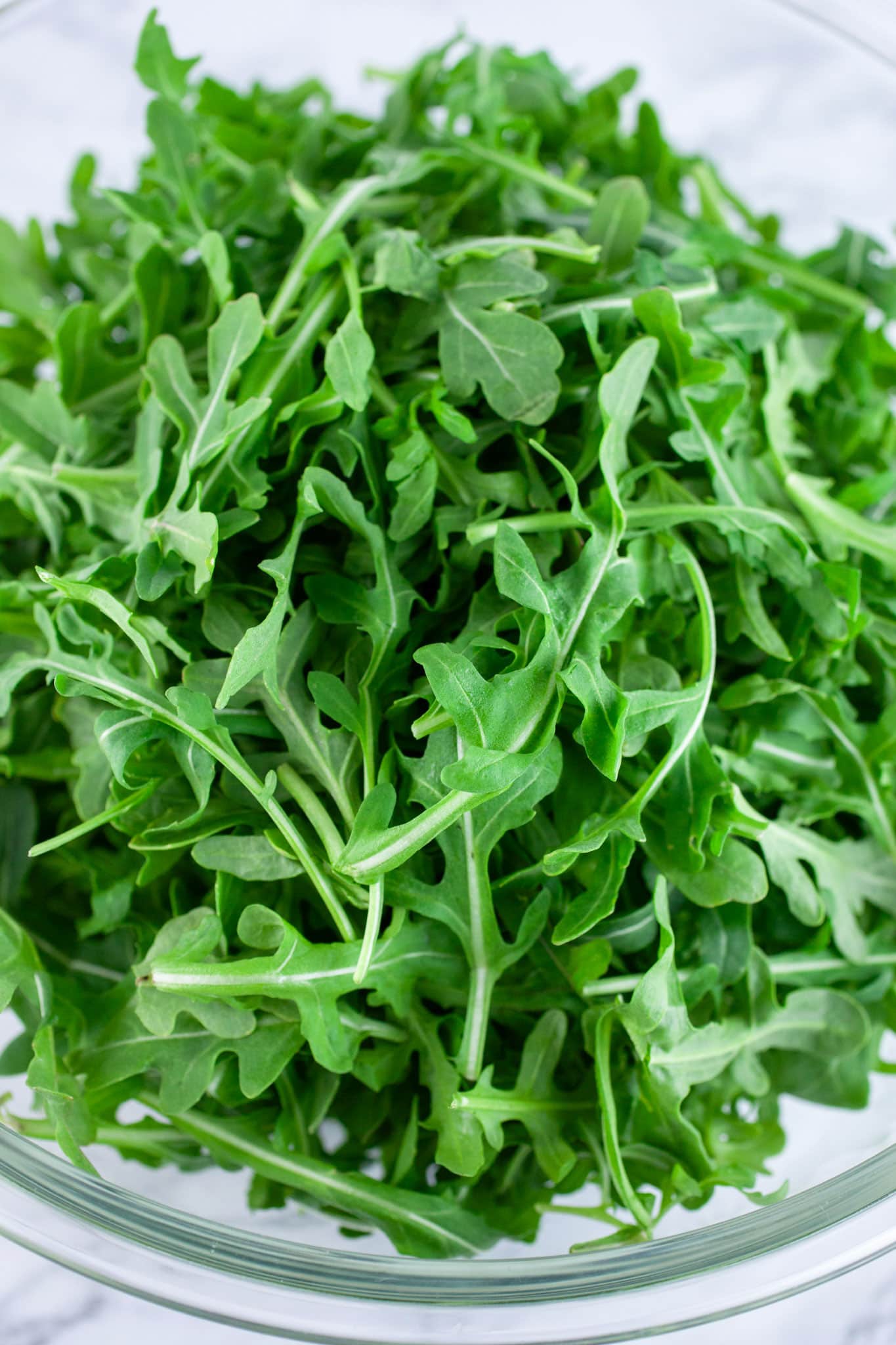 Baby arugula in large glass bowl.