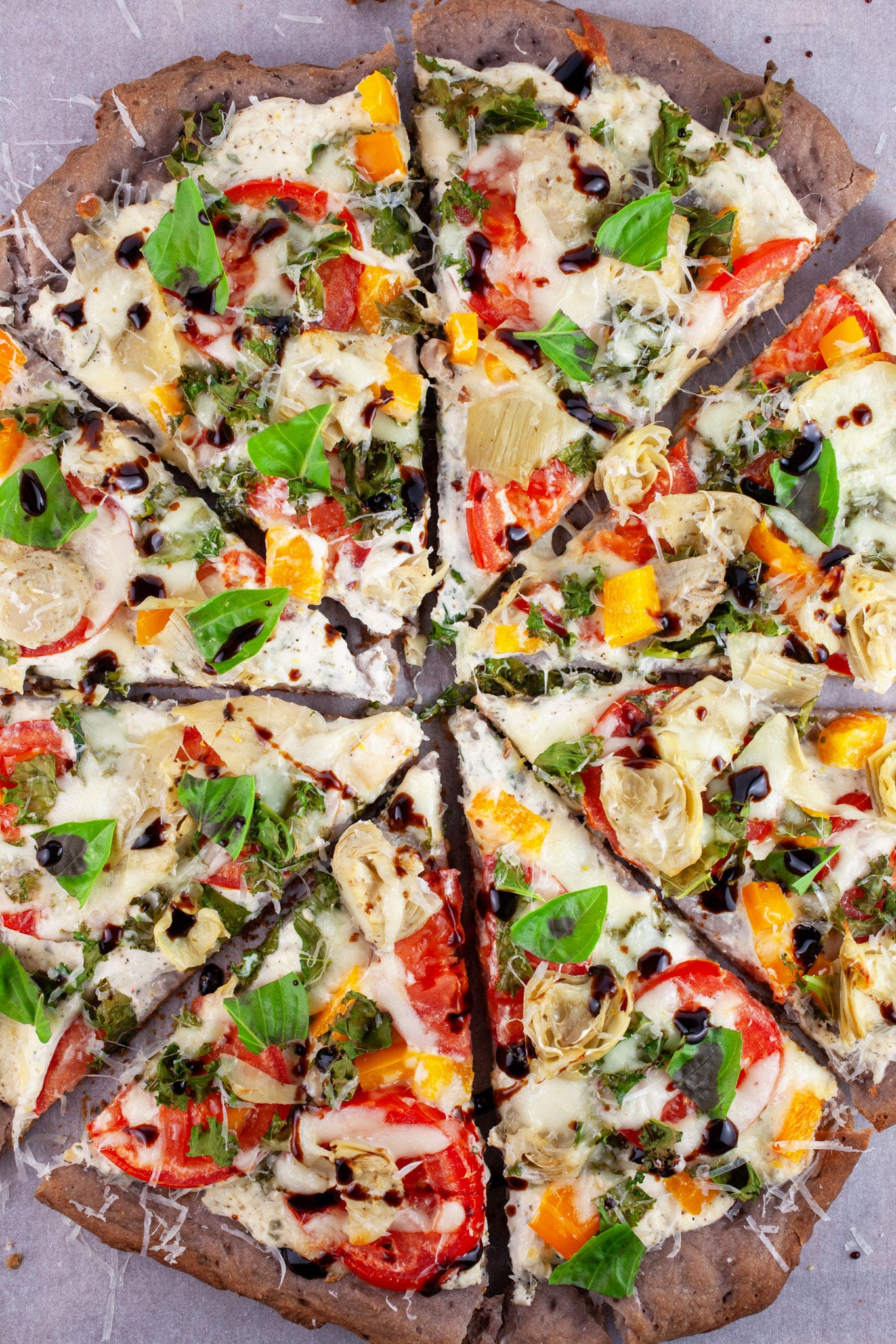 Sliced Farmers Market Pizza garnished with fresh basil and balsamic glaze.