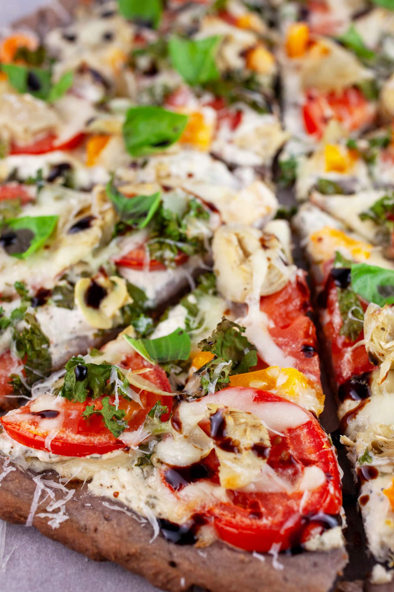 Sliced Farmers Market Pizza garnished with fresh basil and balsamic glaze.