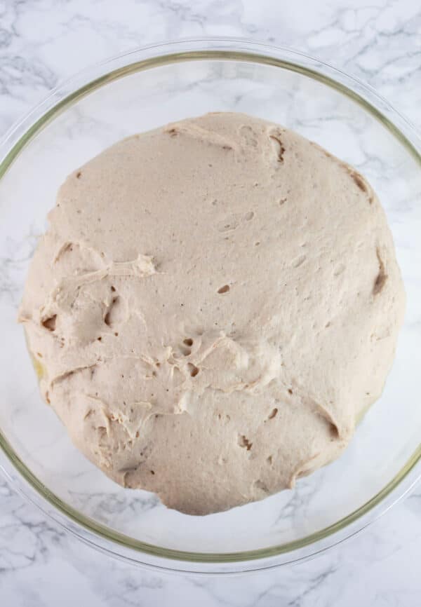 Gluten free pizza dough rising in glass bowl.