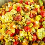 Tomato corn avocado salad in ceramic bowl with spoon.