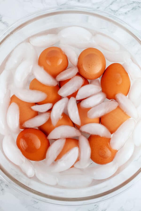 Hard boiled eggs in large glass bowl of ice water.