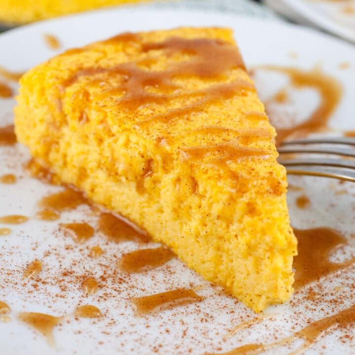 Slice of crustless pumpkin cheesecake with caramel sauce on white plate with fork.