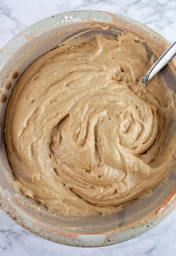 Gluten free apple cake batter in ceramic bowl with spoon.