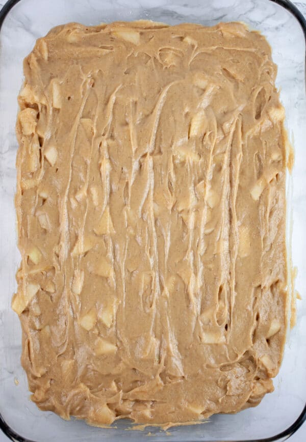 Apple cake batter in glass baking dish.