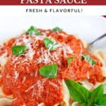 Roasted tomato sauce over pasta garnished with Parmesan cheese and fresh basil in white bowl with fork.