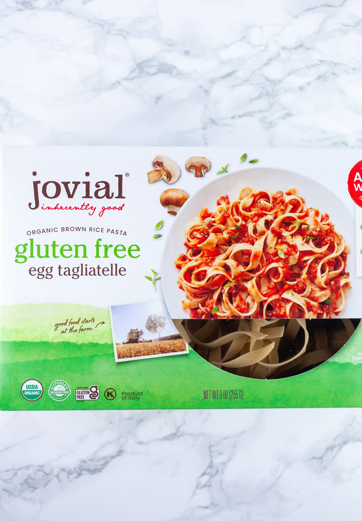 Box of gluten free tagliatelle pasta on white surface.