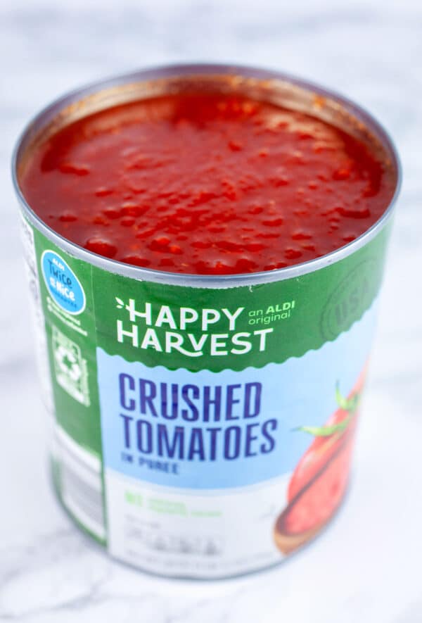 Open can of crushed tomatoes on white surface.