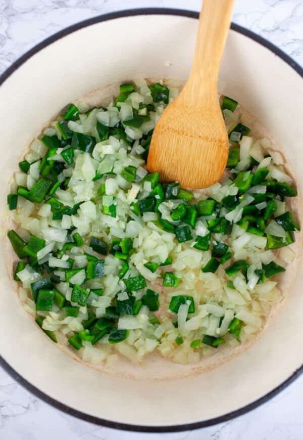 Minced garlic, onions, jalapeno and poblano peppers sauteed in Dutch oven with wooden spatula.