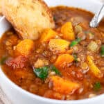 Instant Pot lentil soup in white bowl with spoon with toasted crostini.